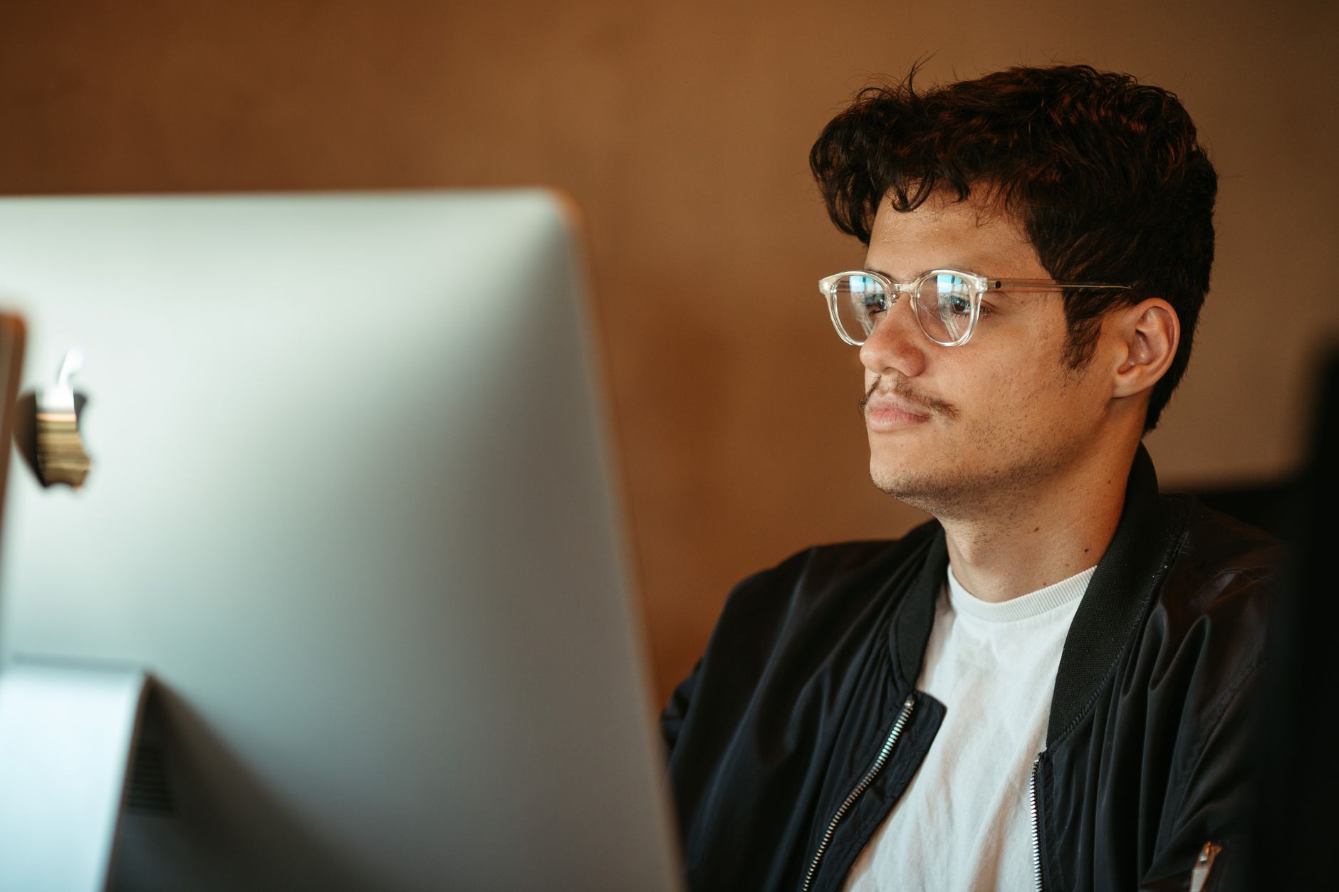 En mand med briller ser koncentreret på en computerskærm
